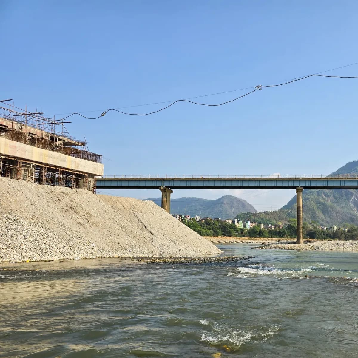 Steel bridge carrying a road across a wide braided river in western Nepal
